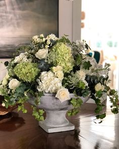 a vase filled with white and green flowers on top of a wooden table