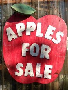 an apple for sale sign hanging on the side of a building