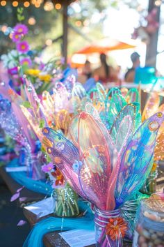 there are many vases with flowers in them on the table at this outdoor event