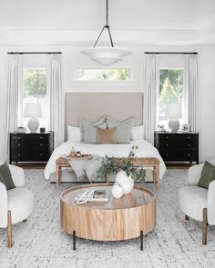 a bedroom with white walls and furniture in the center, along with two chairs and a coffee table