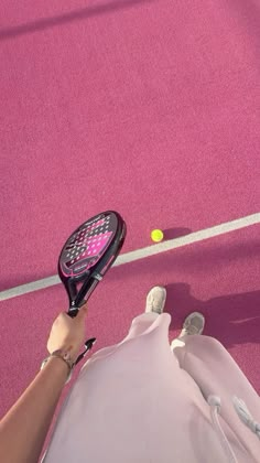 a person holding a tennis racquet on top of a pink court