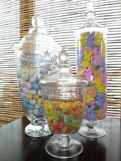 three glass jars filled with candies on top of a table next to each other