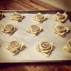 there are many rolled up flowers on the cookie sheet