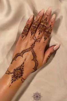 a woman's hand with henna tattoos on it