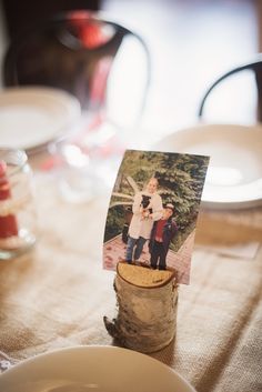 an old photo is placed on top of a tree stump at the center of a table