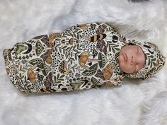 a baby doll that is laying down on a white furnishing with an animal print wrap around it's body