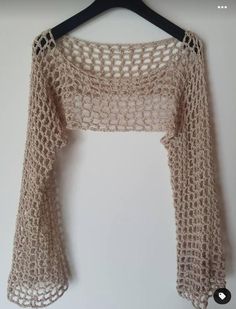 a crocheted top hanging on a hanger