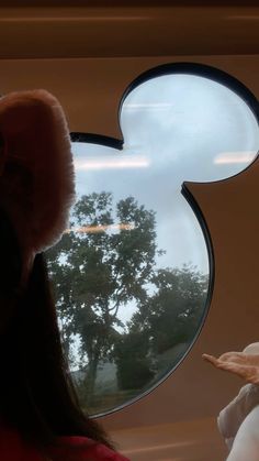 a girl is looking out the window at mickey mouse