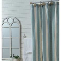 a white sink sitting under a bathroom mirror next to a shower curtain with blue and beige stripes on it