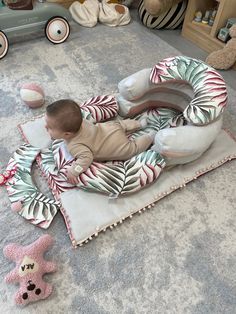 a baby laying on top of a blanket next to stuffed animals and other toys in a room