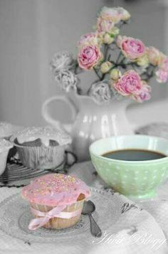 a cup of coffee and a pink frosted donut on a lace tablecloth