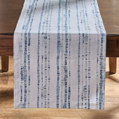 a wooden table with a white and blue striped table runner on top of the table