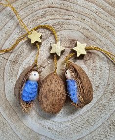 two little blue birds are in the nest with some gold stars on it's string