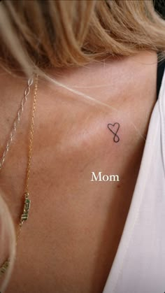 the back of a woman's neck with a small heart tattoo on her left shoulder