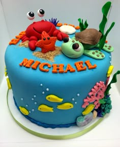 there is a blue cake decorated with sea animals and fish on the bottom, along with words that read michael