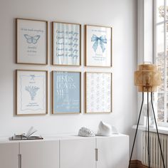 four framed pictures hang on the wall above a white cabinet in a room with windows