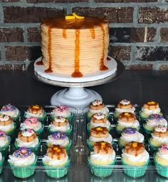 cupcakes and cake on display in front of brick wall