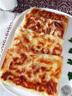 three slices of pizza on a white plate with parsley next to it and a glass of milk in the background