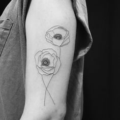 a black and white photo of three flowers on the left arm, with an eye in the center