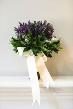 a bouquet of flowers is tied up on a mantel with a white ribbon around it