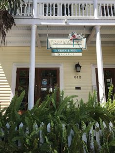 a white building with a sign that says tropical house on it's front porch