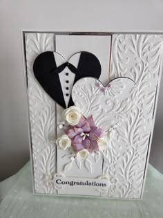 a wedding card with two hearts and flowers on the front, decorated with white paper