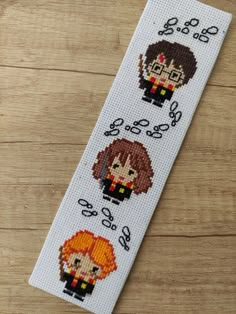 a cross stitch bookmark with three different characters on it