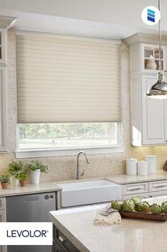 a kitchen with white cabinets and an island in front of the sink is lit by two pendant lights