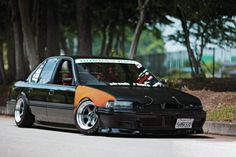 a black and orange car parked on the side of a road next to some trees