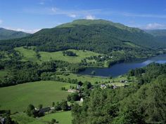 an aerial view of a lake surrounded by lush green hills and trees in the distance