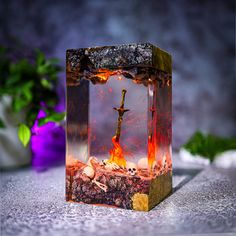 a glass block with a cross in it on top of a table next to flowers