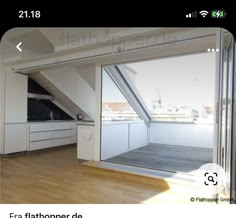 an open room with wooden flooring and white cabinets in front of a large window