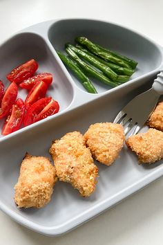 two trays filled with different types of food on top of a white table next to green beans and tomatoes