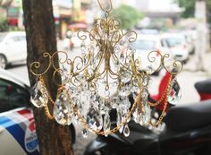 a chandelier hanging from the side of a tree in front of parked cars