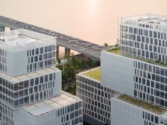 an aerial view of some buildings and a bridge in the background with cars on it