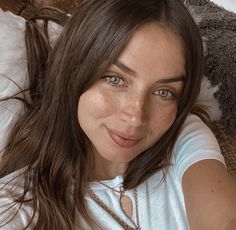 a close up of a person laying on a bed with a stuffed animal behind her