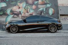 a black sports car parked in front of a mural