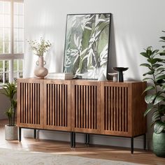 a wooden cabinet sitting in front of a window next to potted plants and vases