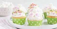 several cupcakes with white frosting and sprinkles on a plate