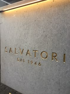 the salvattorii building sign is lit up in gold on a gray wall