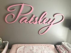 a baby's room with a pink name sign on the wall