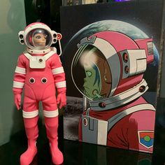 an astronaut doll standing next to a painting