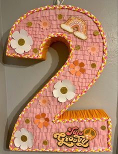 the number two is made out of pink paper and decorated with gold, orange, and white flowers