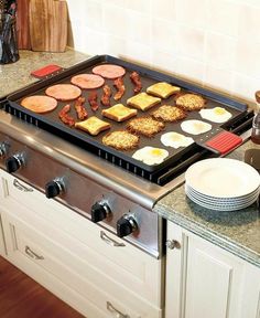 a stove top with food cooking on it in a kitchen next to plates and utensils