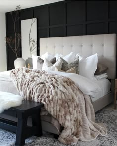 a large bed with white and gray blankets on it's headboard in a bedroom