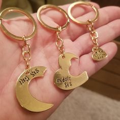 three gold keychains with the names of two different people and one has a crescent on it