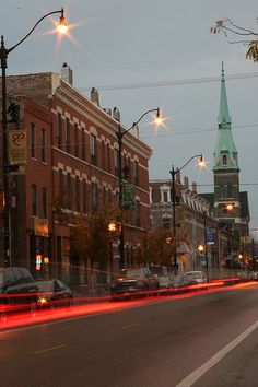 an empty city street at dusk with cars passing by