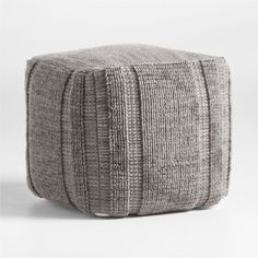 a square ottoman made out of grey fabric