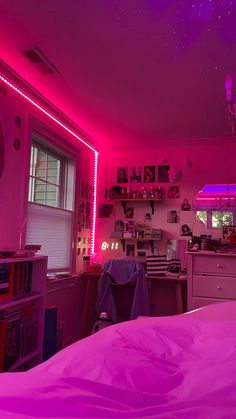 a bedroom with pink lighting and pictures on the wall