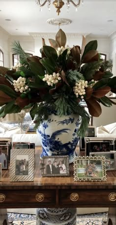 a blue and white vase sitting on top of a wooden table next to a bunch of pictures